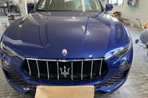 Frontansicht eines blauen Maserati in einer Garage, die den Kühlergrill und die Motorhaube zeigt.