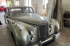Vintage-Silber-Klassiker in einer Garage, Vorderansicht mit Chromgrill und runden Scheinwerfern.