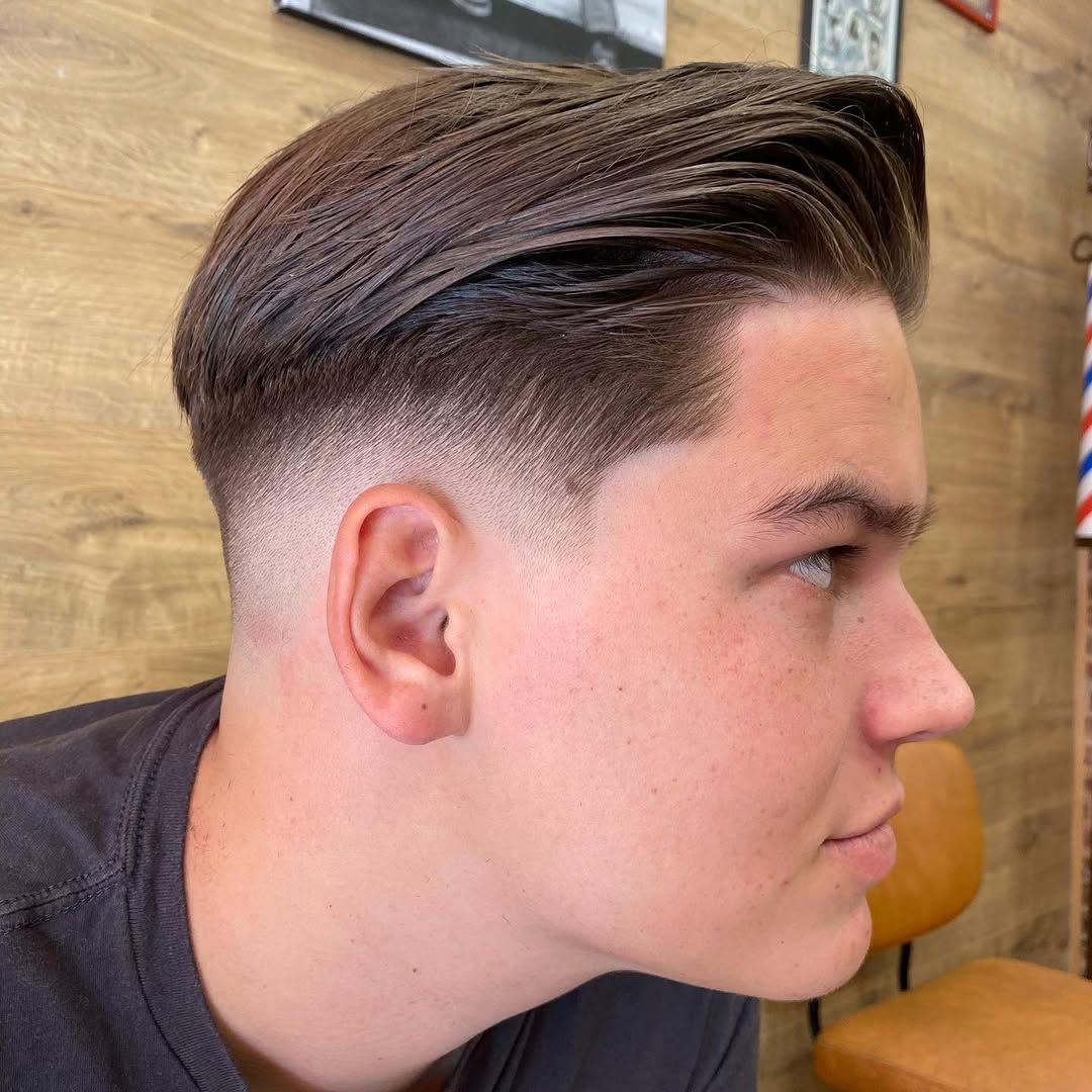 Un coiffeur coupe les cheveux d'un homme brun