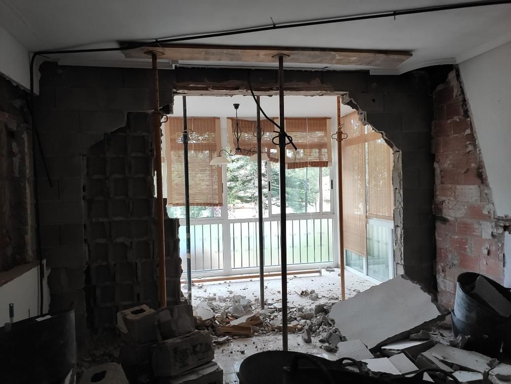 Habitación en reformas con un agujero en la pared. Unas vigas de soporte provisionales sostienen una viga. 
