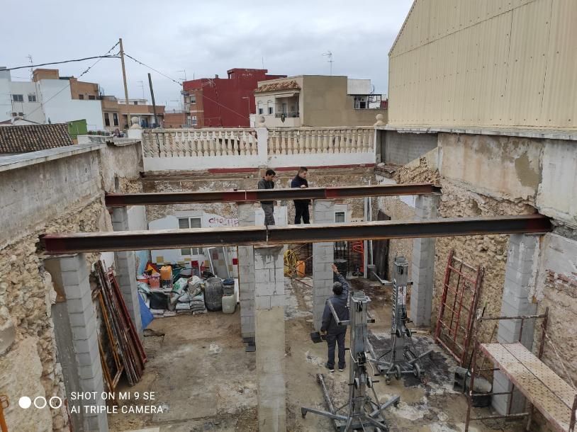 Sitio de construcción con trabajadores, vigas de soporte instaladas, estructura abierta.