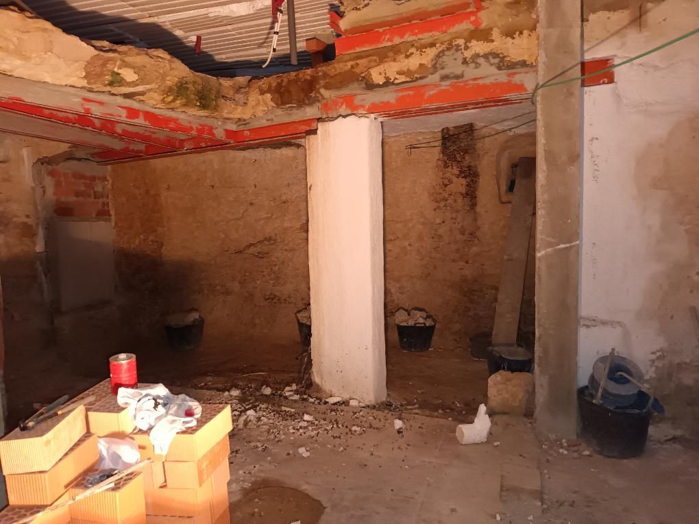 Interior de una habitación en construcción, con vigas vistas y pilares de soporte de hormigón.