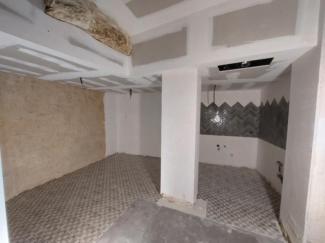 Construcción interior en proceso, habitación con vigas de techo a la vista y piso texturizado.