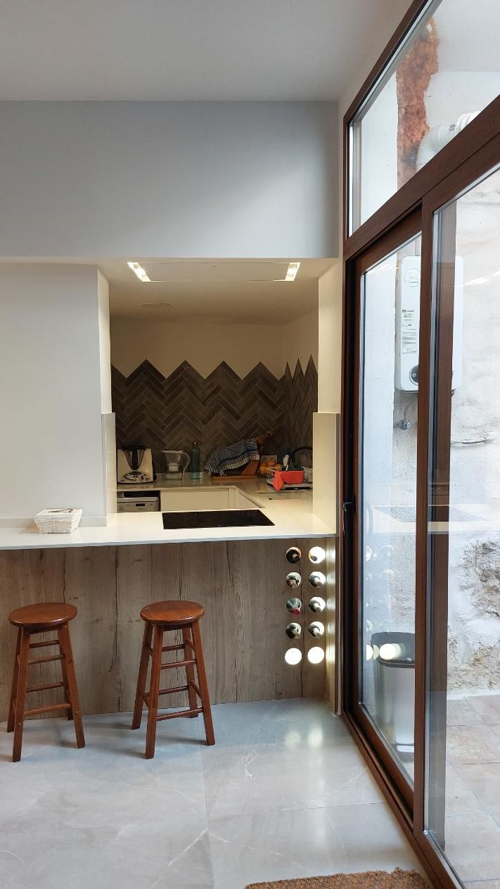 Cocina con barra de desayuno, taburetes y ventana al exterior. Combinación de colores gris y blanco.