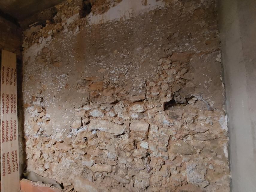 Muro de piedra vista con eflorescencias blancas.