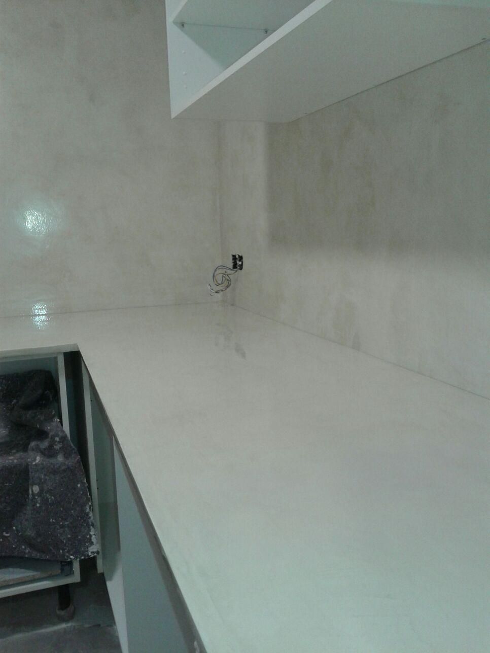 Encimera y gabinetes blancos en una cocina, con una pared gris claro.