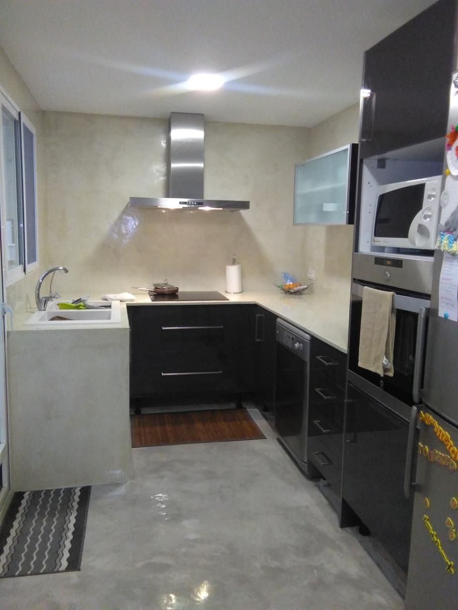 Cocina moderna con gabinetes oscuros, electrodomésticos de acero inoxidable y encimeras claras.