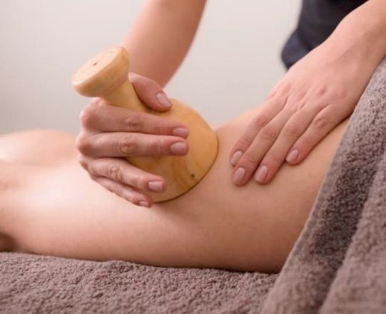 Una mujer está recibiendo un masaje de madera en su pierna.
