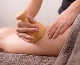 Una mujer está recibiendo un masaje de madera en su pierna.