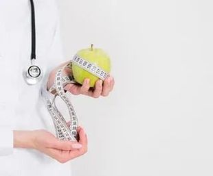 Un médico sostiene una manzana con una cinta métrica alrededor de ella.