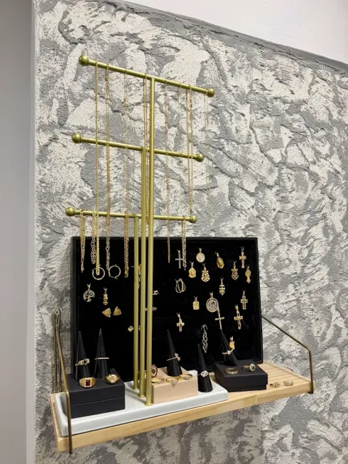 Expositor de joyas de oro con collares y pendientes sobre bandejas de terciopelo negro.