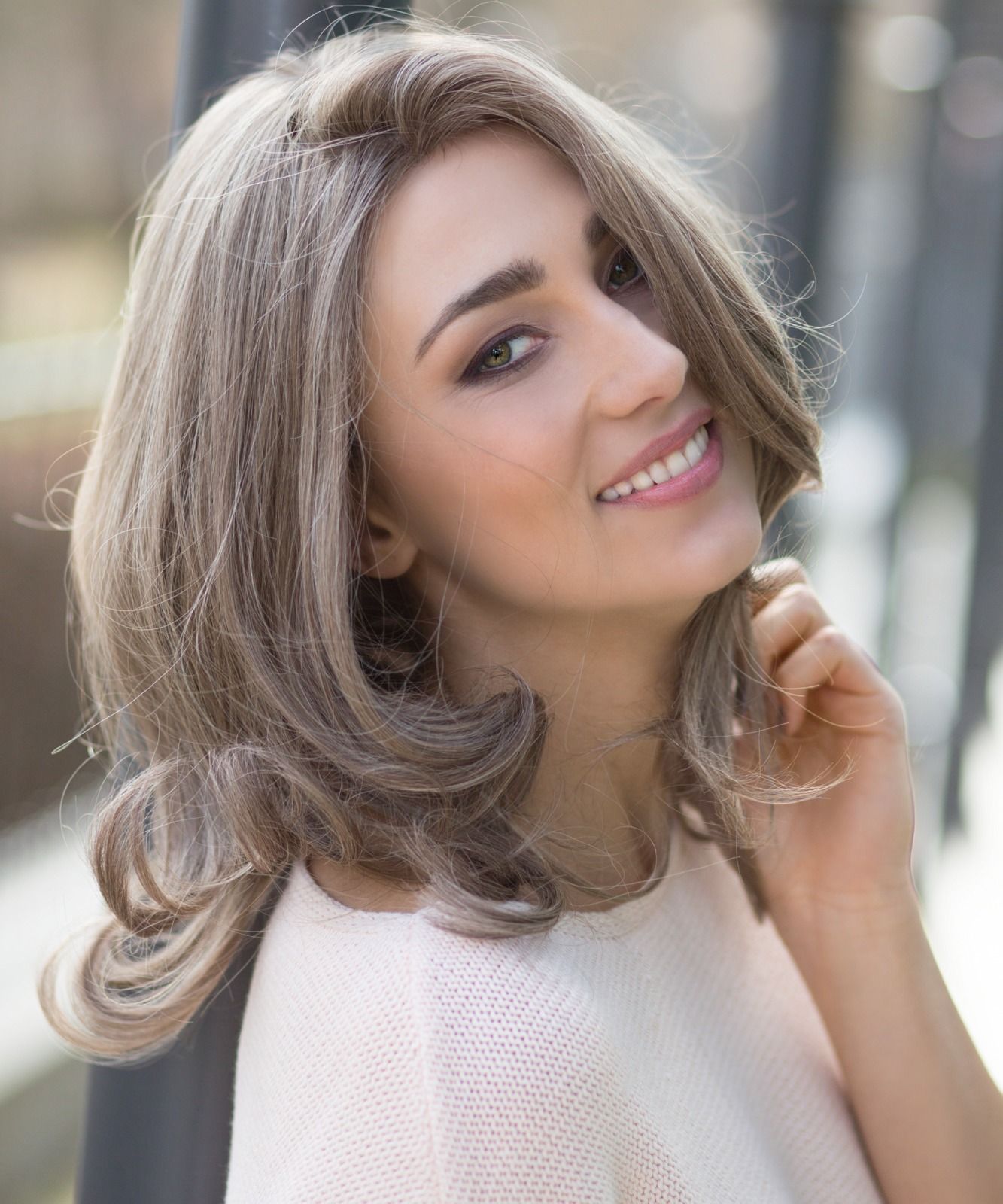 Eine Frau mit Perücke lächelt und schaut in die Kamera.