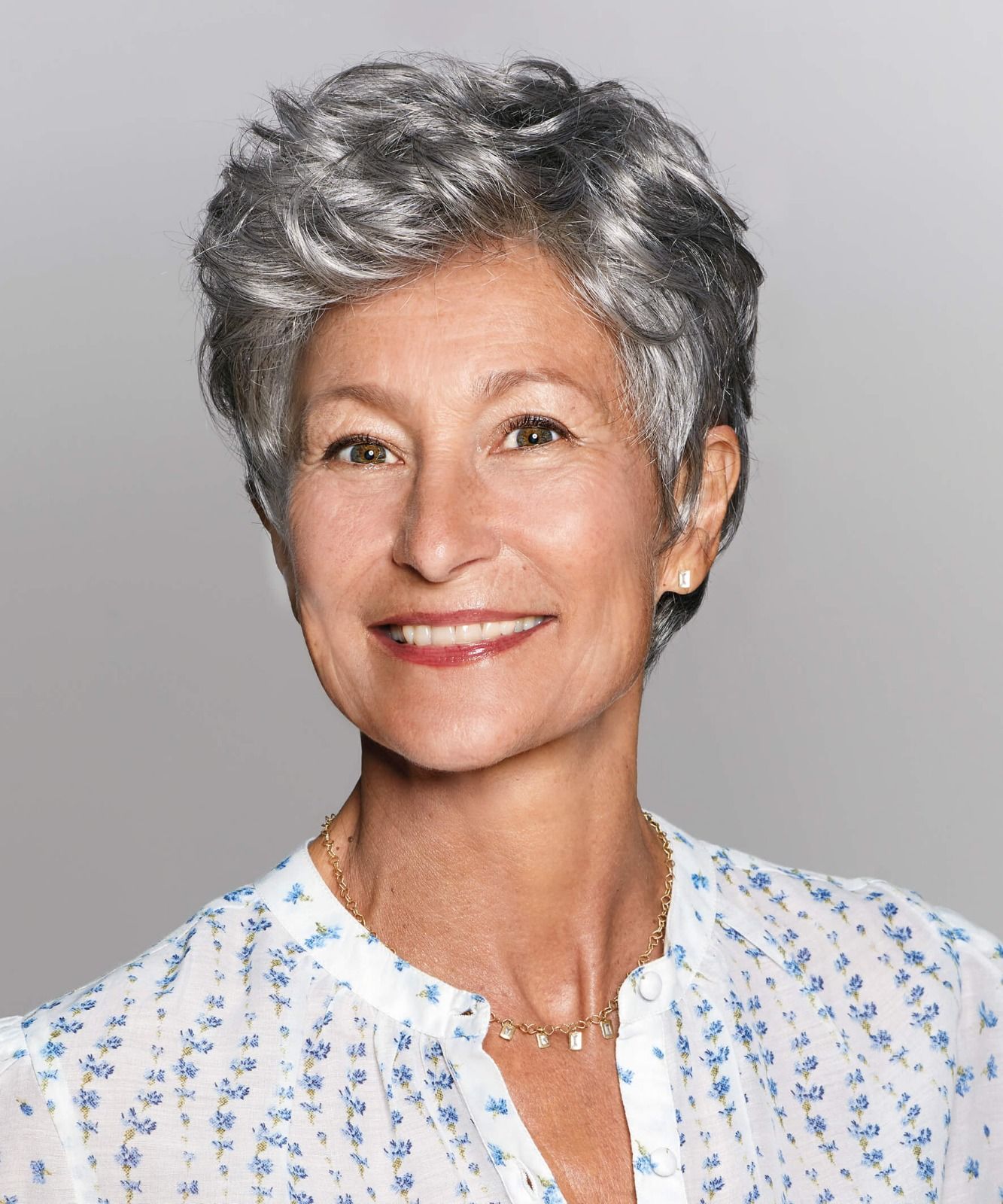 Eine Frau mit kurzen grauen Haaren lächelt in die Kamera.
