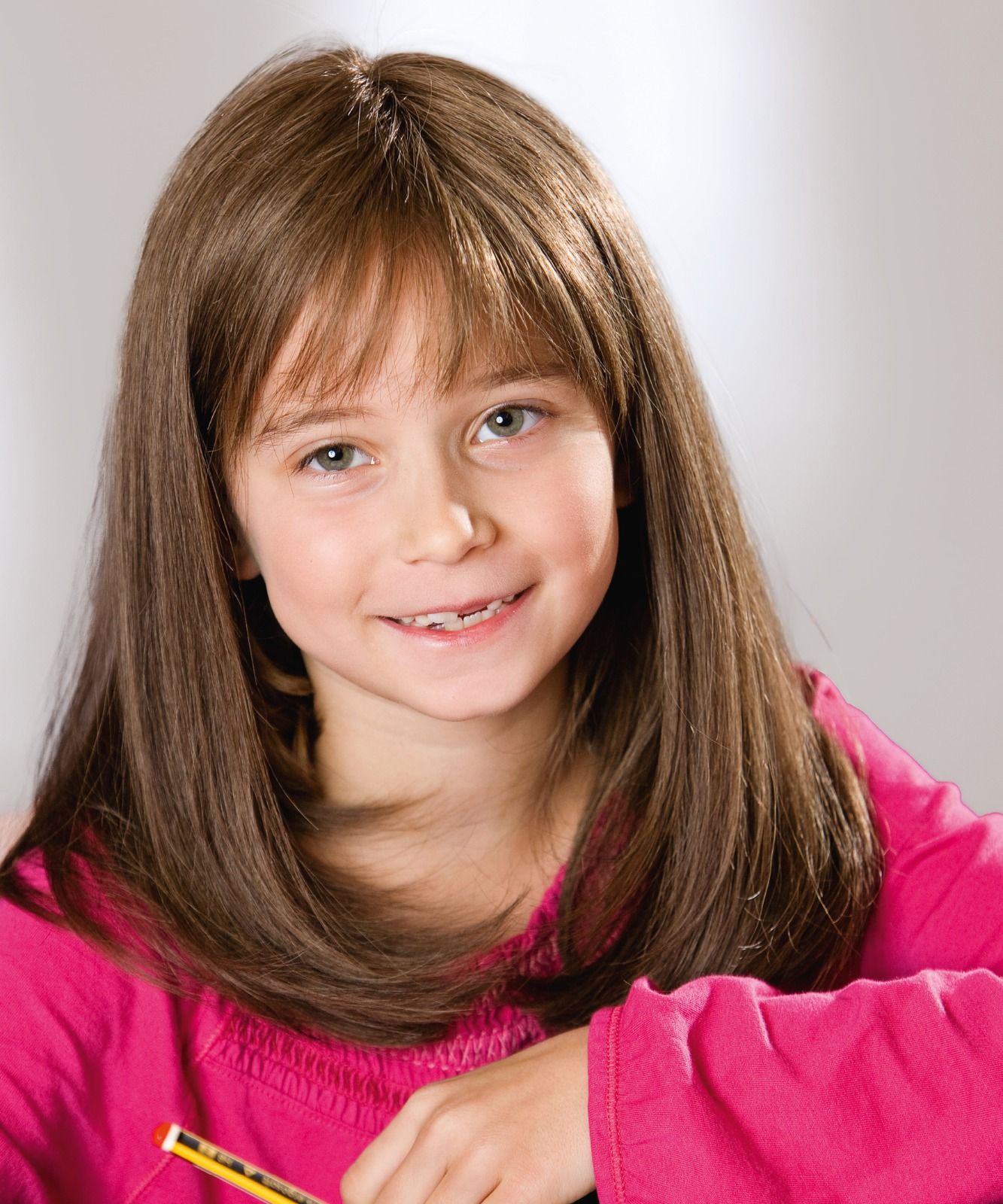 Ein junges Mädchen in einem rosa Hemd hält einen Bleistift