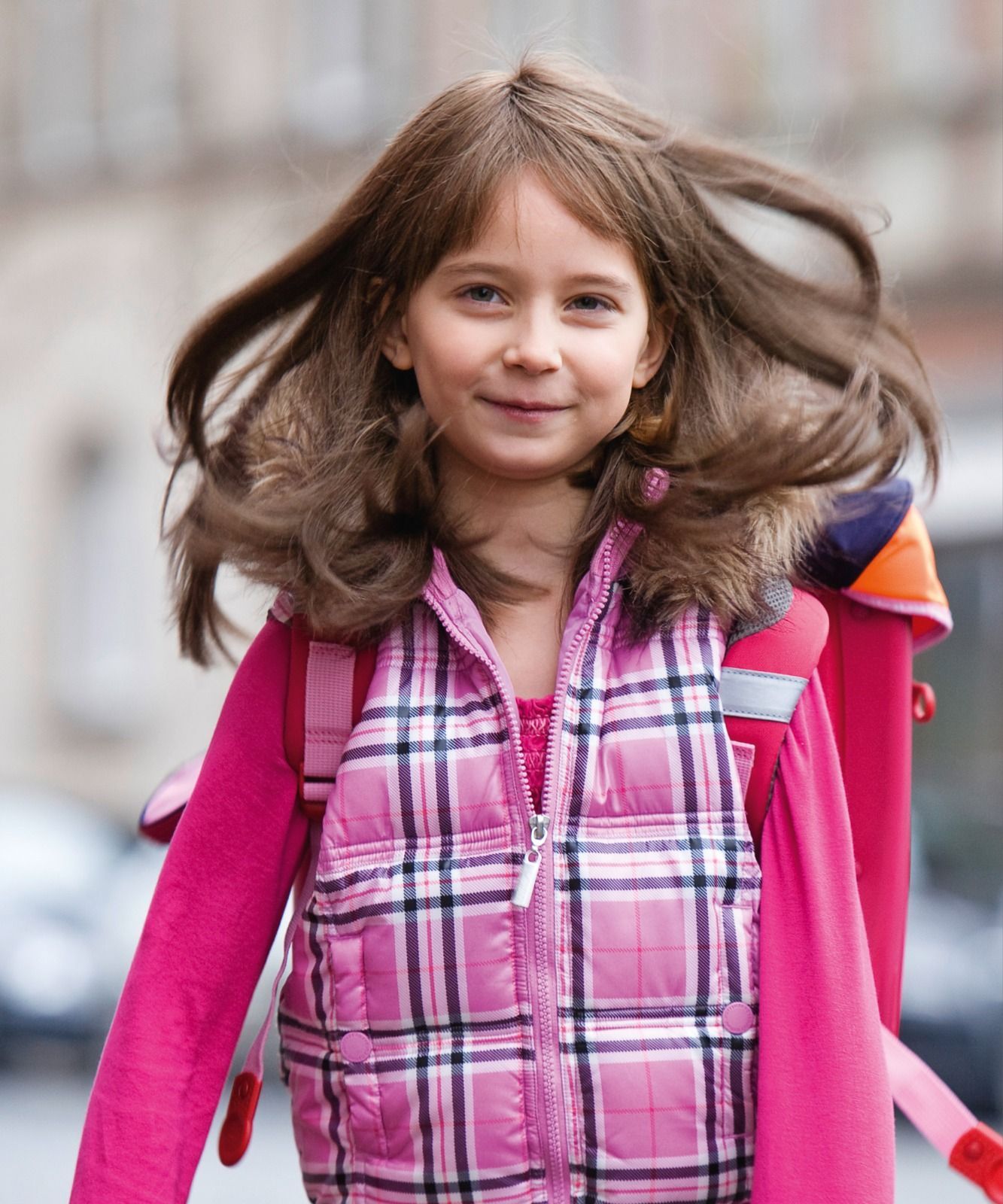 Ein kleines Mädchen mit einer rosa Weste und einem Rucksack