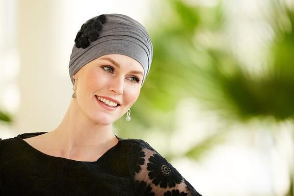 Eine Frau mit Turban und schwarzem Kleid lächelt.