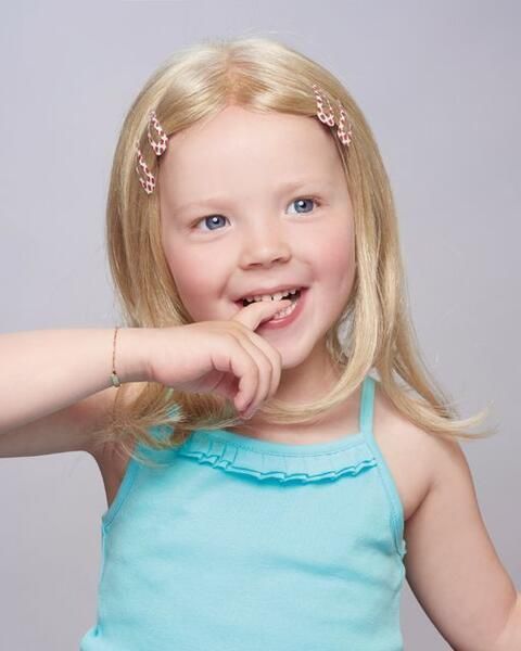 Ein kleines Mädchen mit einer Perücke und einem blauen Tanktop