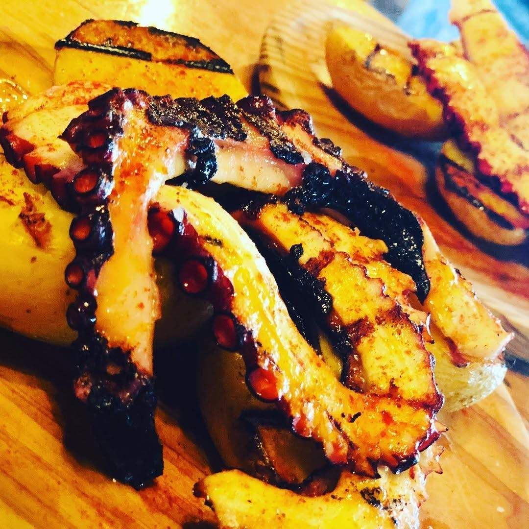 Filetes de pescado a la parrilla con condimento ahumado sobre una tabla de cortar de madera.