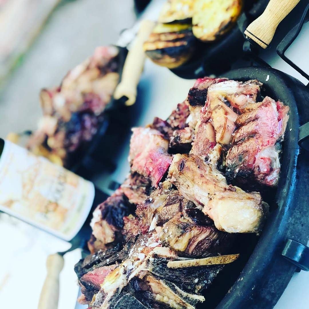 Brochetas de carne a la parrilla y trozos de bistec chisporroteando en una sartén barbacoa.
