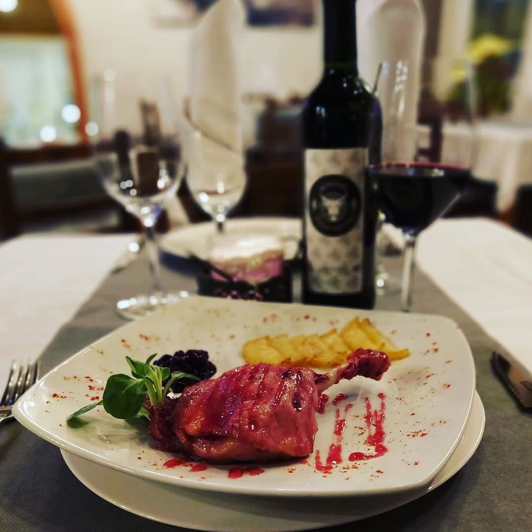 Cena de bistec emplatado con vino en una mesa de restaurante con iluminación tenue.