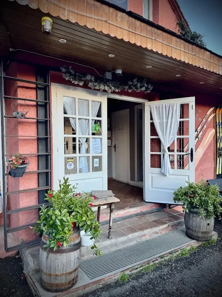 Acogedora entrada con puerta blanca, toldo a rayas, macetas con flores y barriles de madera rústicos.