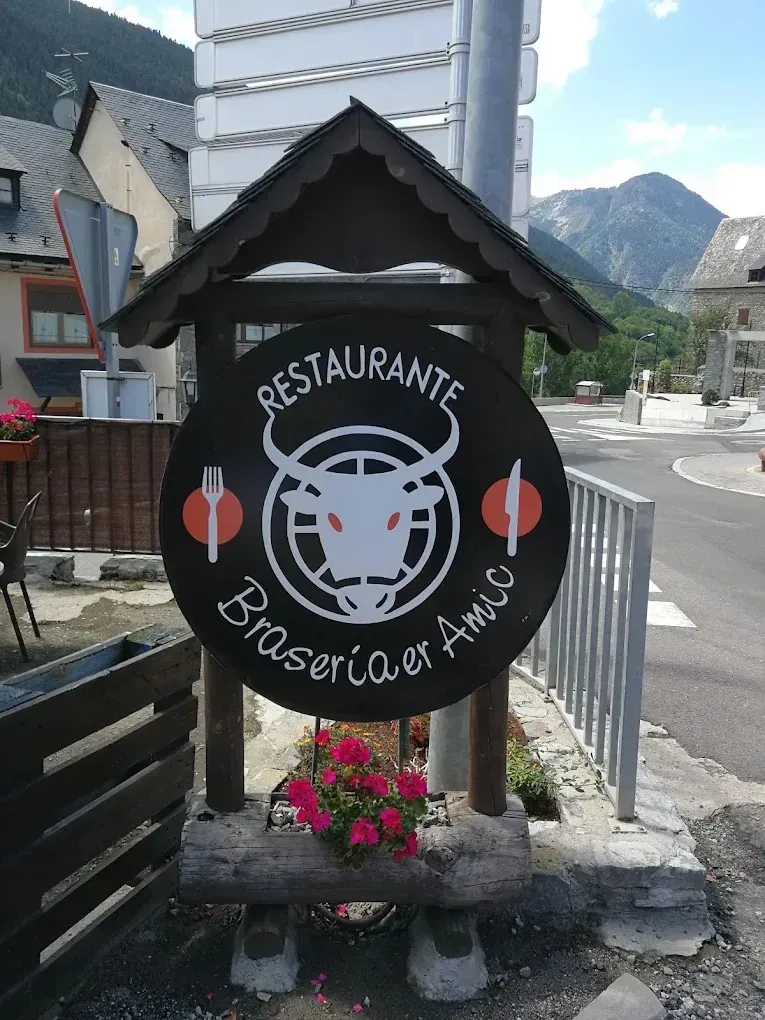 Letrero de restaurante con el logo de una vaca, utensilios rojos y fondo de un pueblo de montaña.