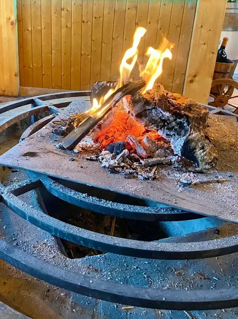 Pequeña fogata ardiendo sobre un brasero de metal con brasas incandescentes