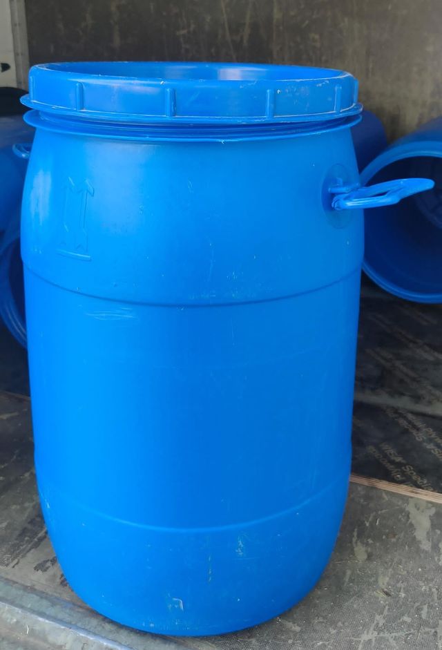 Un barril de plástico azul con tapa y asas azules está sobre una mesa.