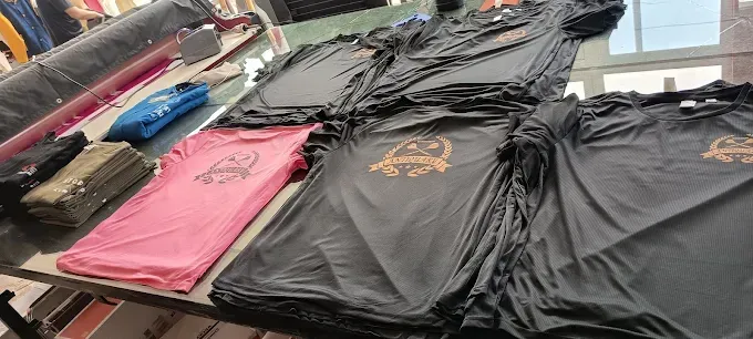 Camisetas rosas y negras con diseño estampado están apiladas sobre una mesa.