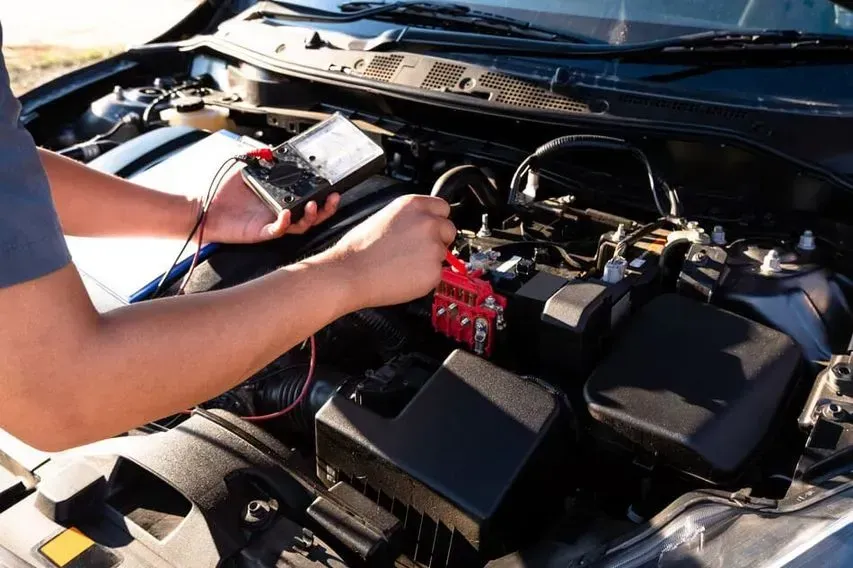 Un hombre está trabajando en el motor de un coche.