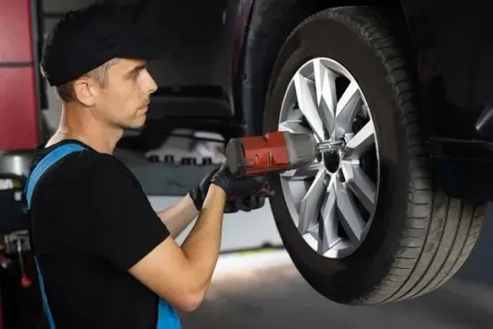 Un hombre está cambiando un neumático de un coche con una llave inglesa.