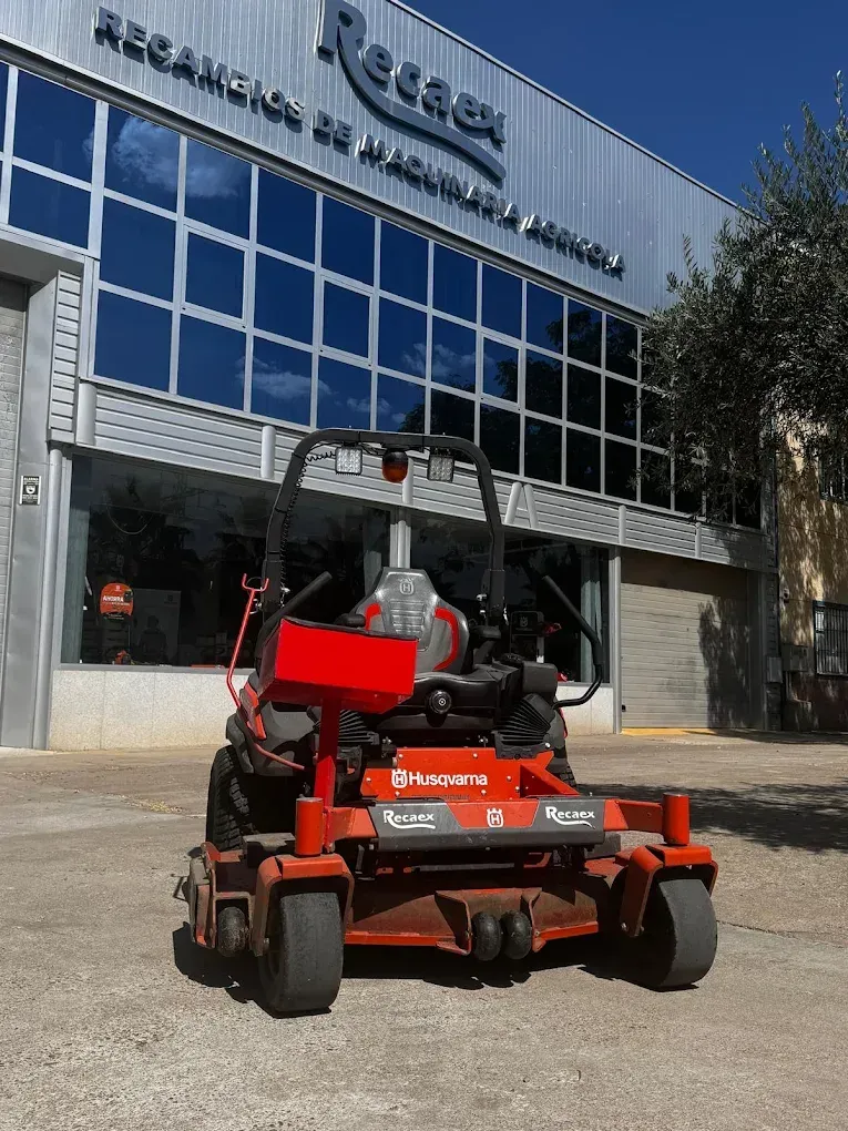 Una plataforma elevadora de tijera naranja está estacionada frente a un edificio con fachada de cristal