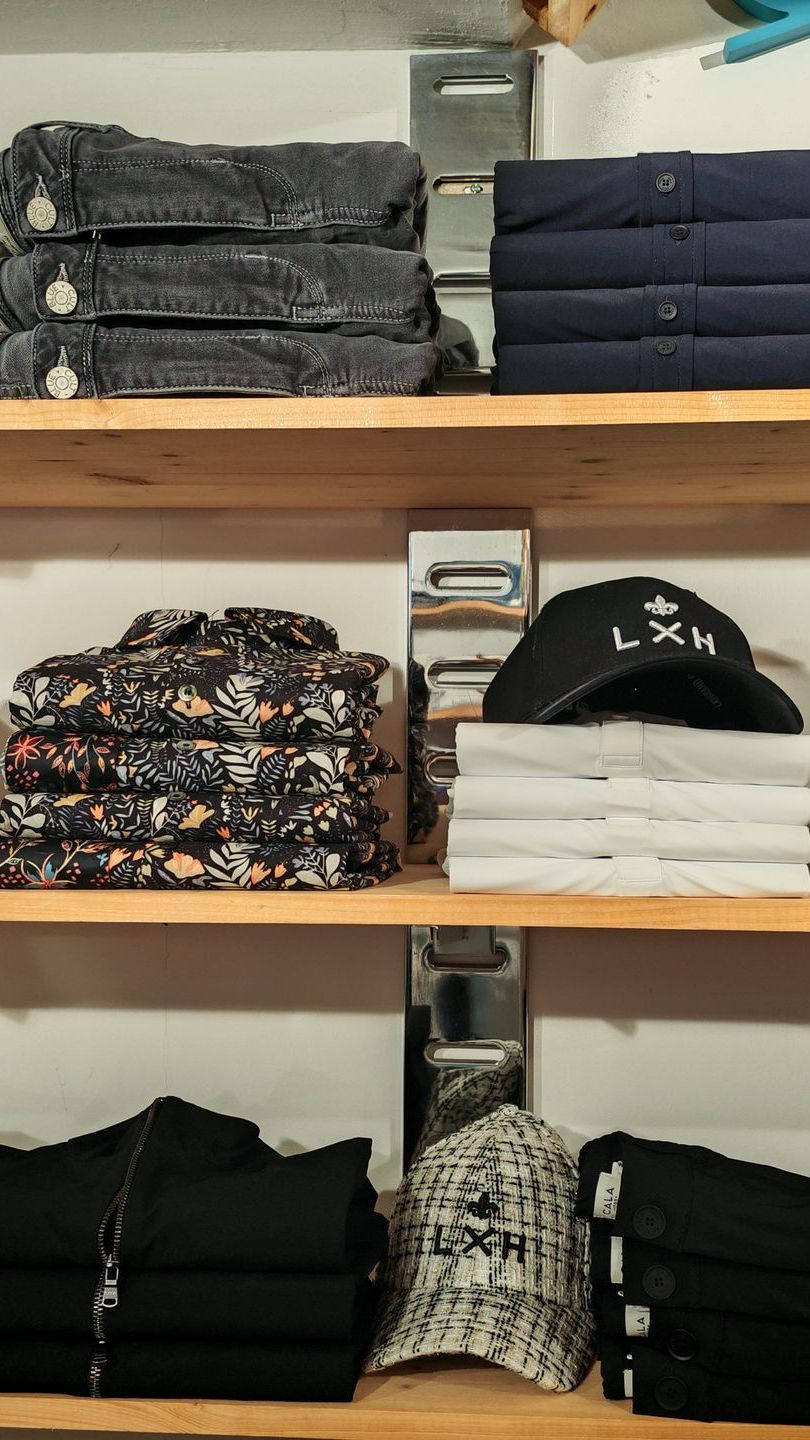 Étagères avec des polos , pantalons, chemises et casquettes