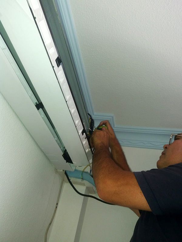 Un hombre está trabajando en un acondicionador de aire en el techo.