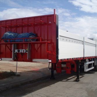 Un camión semirremolque rojo y blanco está estacionado al costado de la carretera.