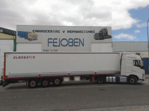 Un camión blanco está estacionado frente a un edificio con un cartel que dice fejoben
