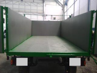 Un remolque verde y gris está estacionado en un almacén.