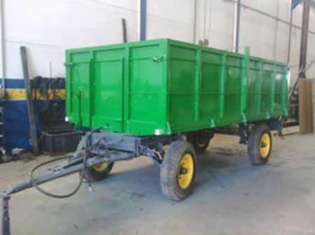 Un remolque verde con ruedas amarillas está estacionado en un garaje.