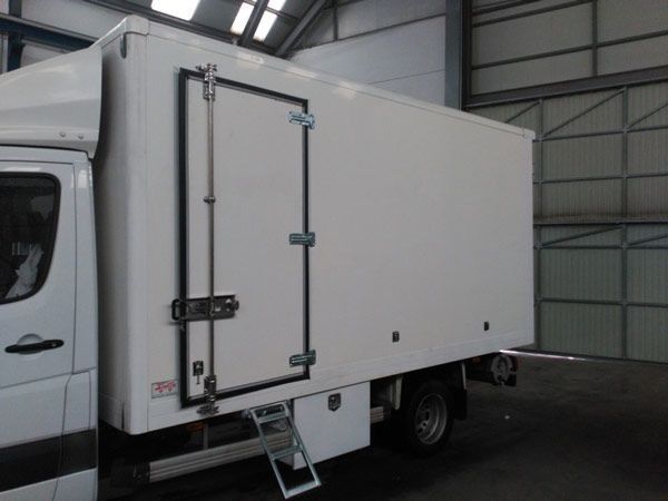 Un camión blanco con una escalera atada al costado.