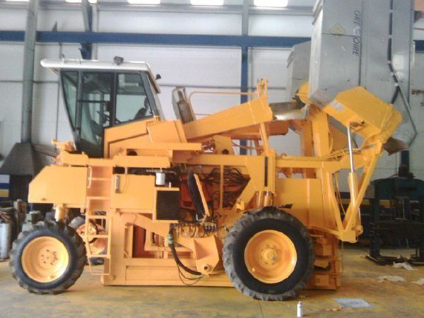 Un gran tractor amarillo está estacionado en un almacén.