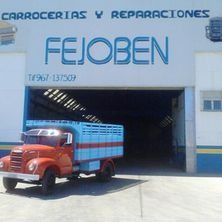 Un camión rojo y azul está estacionado frente a un edificio.