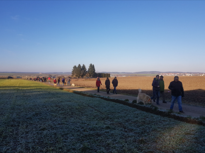 Menschen, die bei Sonnenaufgang unter klarem, blauem Himmel einen frostigen Landweg entlanggehen
