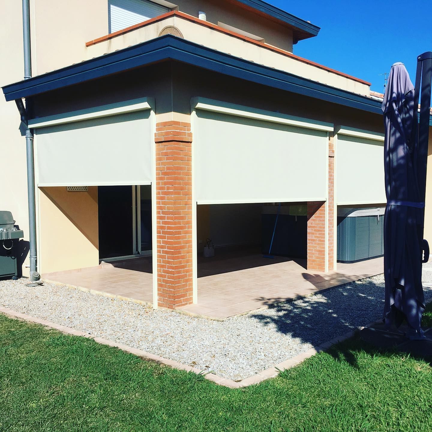 Pergola avec des piliers en brique et stores à moitié fermés