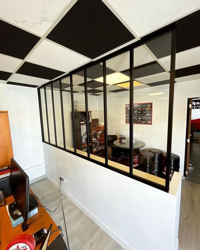 Grande verrière avec une armature en métal qui sépare 2 pièces dans une maison