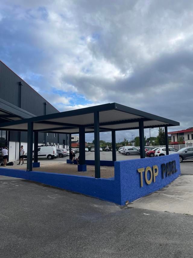 Pergola en démonstration devant le showroom sous un ciel nuageux