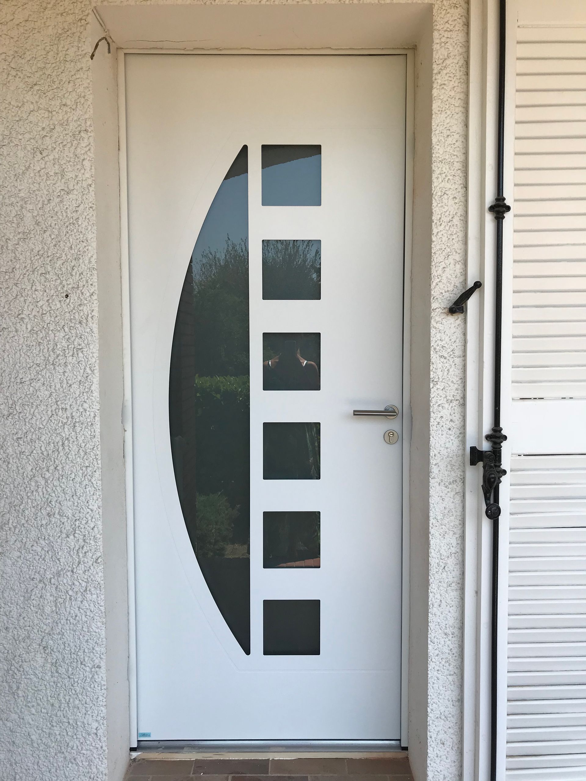 Porte d'entrée blanche avec 4 petites vitres carrées et une grande en demi-lune