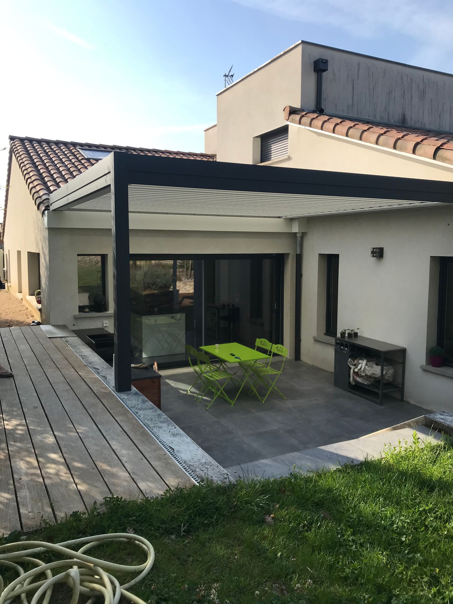 Pergola avec une table et des chaises de jardin