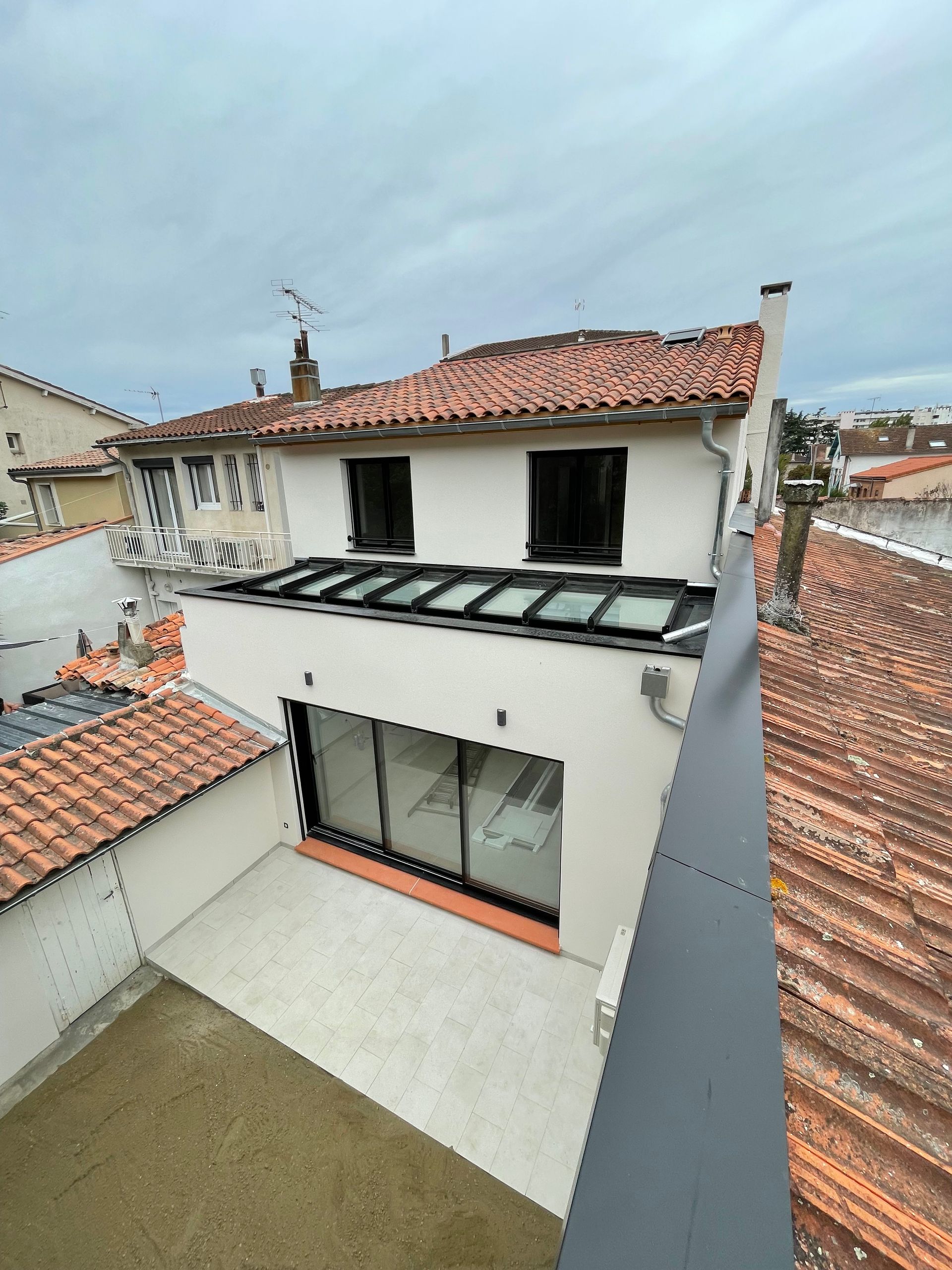 Vue des toits d'une baie vitrée et de fenêtres à l'étage