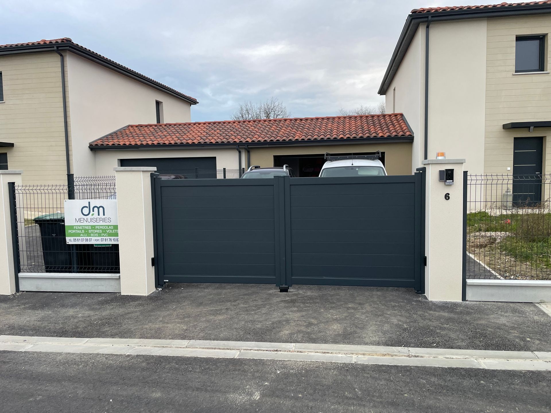 Portail à battants sombre donnant sur la rue