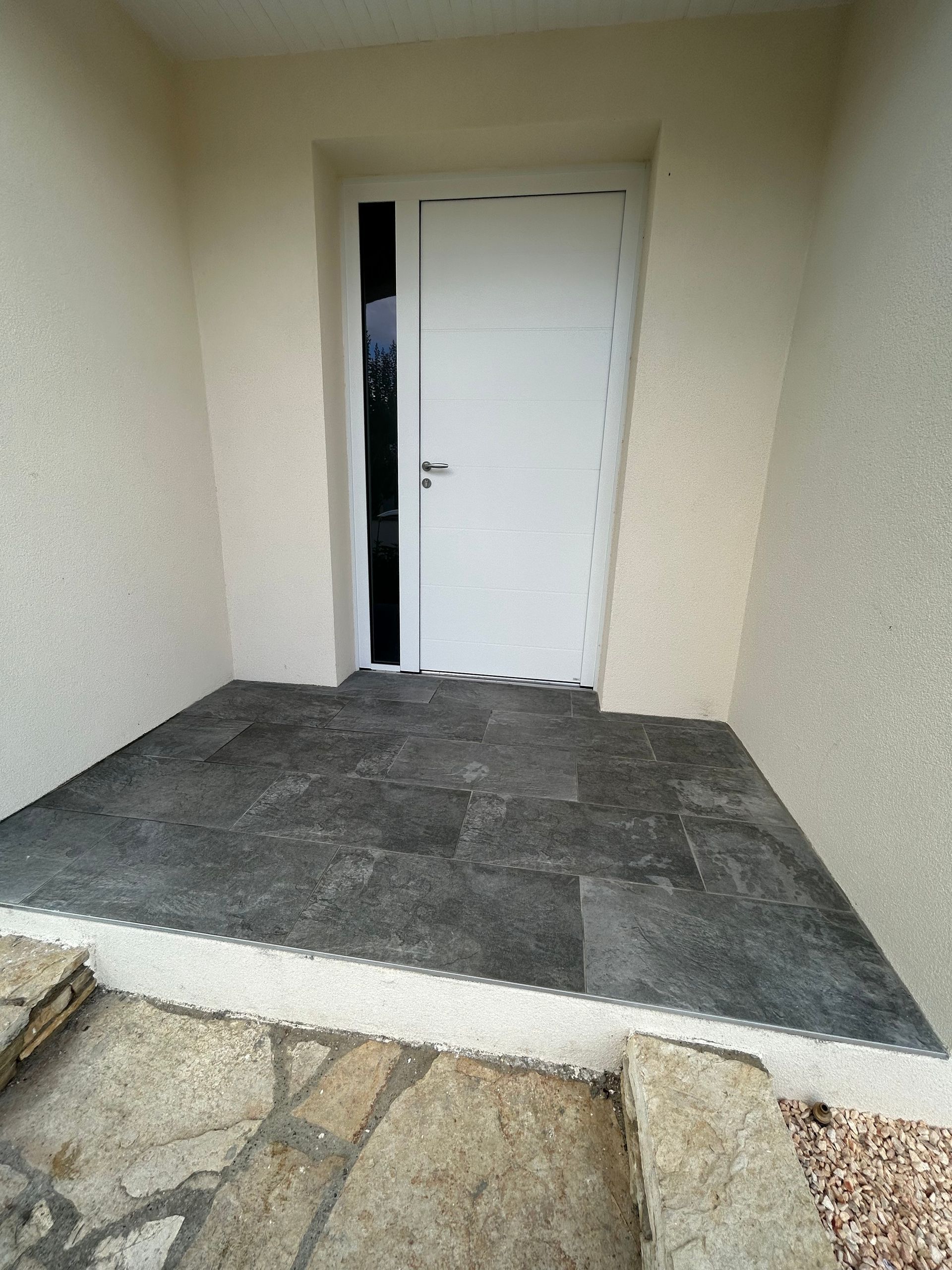 Porte d'entrée blanche avec une ouverture sur toute la hauteur pour faire passer la lumière